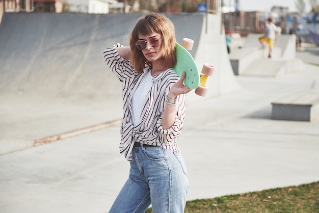 Elegante bella giovane donna con uno skateboard, in una bella giornata di sole estivo.