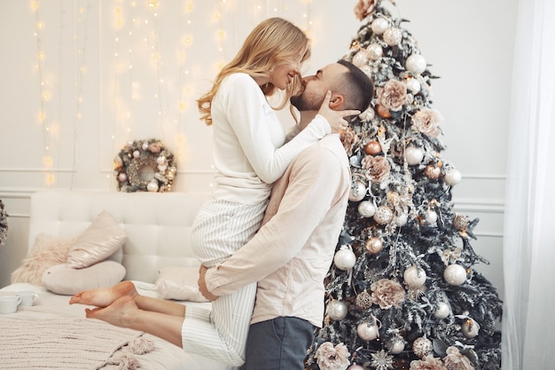 Elegante coppia in piedi a casa vicino all'albero di Natale