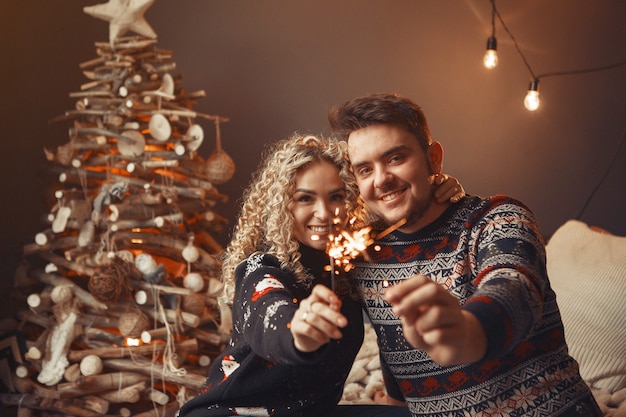 Elegante coppia seduta a casa vicino all'albero di Natale