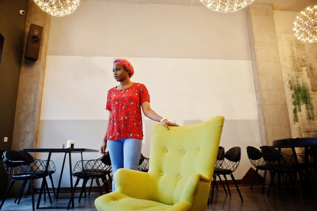 Elegante donna africana in camicia rossa e cappello in posa al coperto