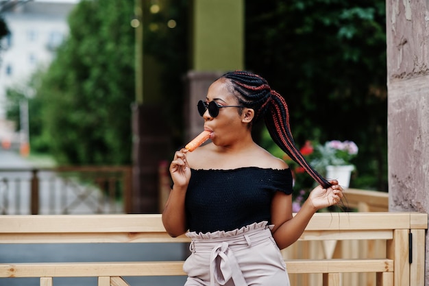 Elegante donna afroamericana in occhiali da sole con gelato