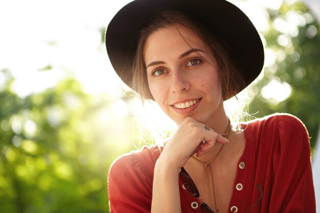 Elegante donna che indossa camicetta rossa e grande cappello