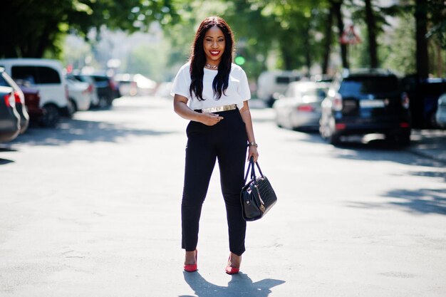 Elegante donna d'affari afroamericana con borsa per le strade della città