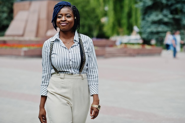 Elegante donna d'affari afroamericana in pantaloni con reggicalze e camicetta poste all'aperto