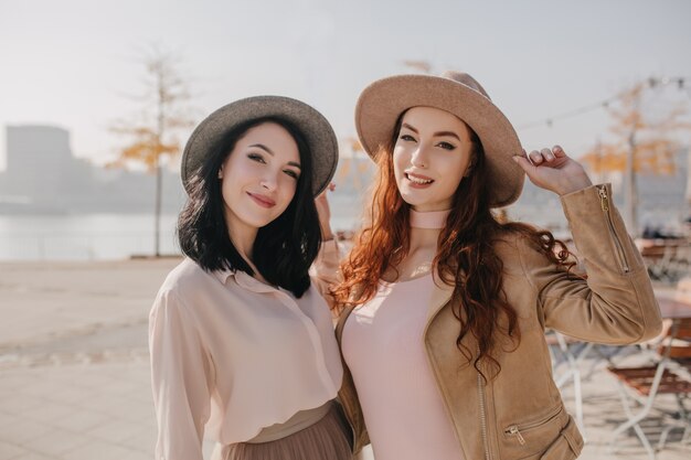 Elegante donna dai capelli rossi in abito beige in posa con un amico sulla natura