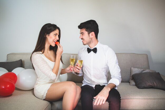 Elegante donna di mangiare una fragola, mentre tostatura con il suo fidanzato