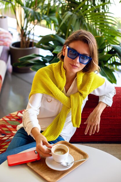 Elegante donna di mezza età che beve caffè mattutino al ristorante mediterraneo.