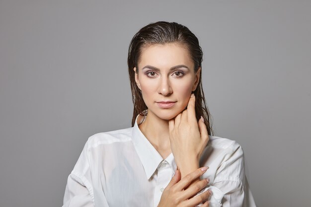 elegante donna maschile attraente in abiti da uomo formali guardando con un sorriso misterioso, toccando il suo viso liscio