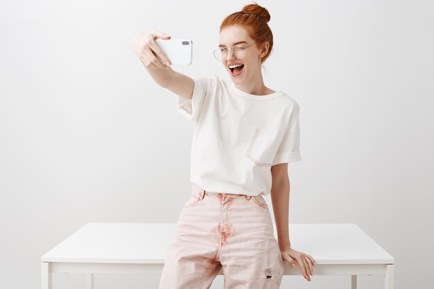Elegante donna redhead prendendo selfie in ufficio