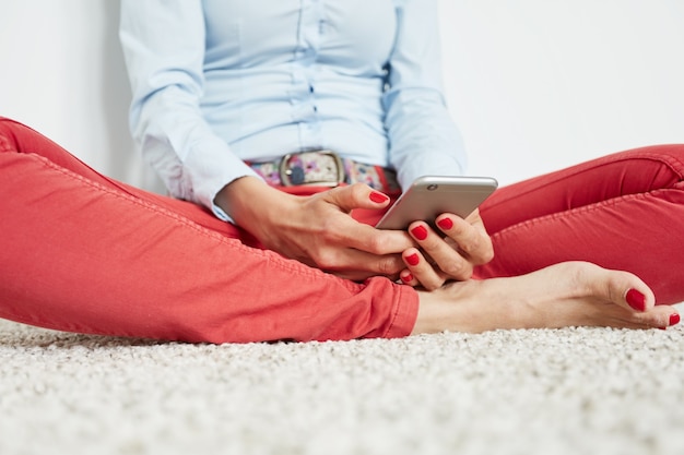 Elegante donna seduta sul pavimento con lo smartphone