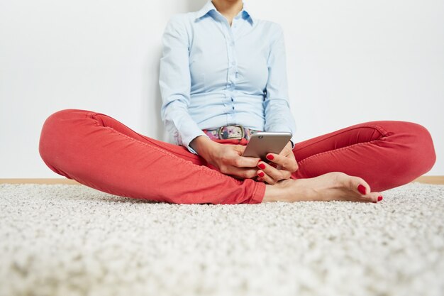 Elegante donna seduta sul pavimento con lo smartphone