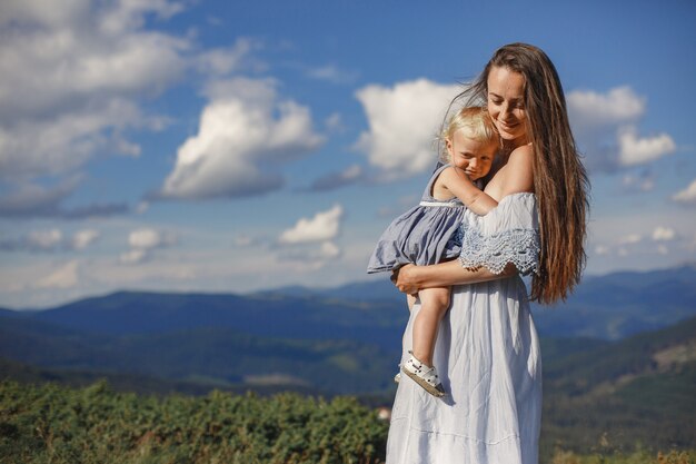 Elegante famiglia in montagna. Mamma e figlia su uno sfondo di cielo. Donna in abito bianco.