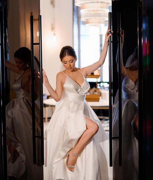 Elegante fidanzata in abito da sposa in posa tra le porte