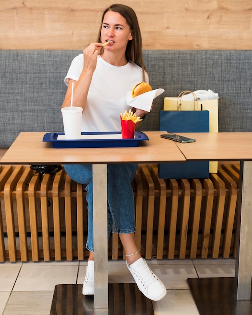 Elegante giovane donna che mangia fast food