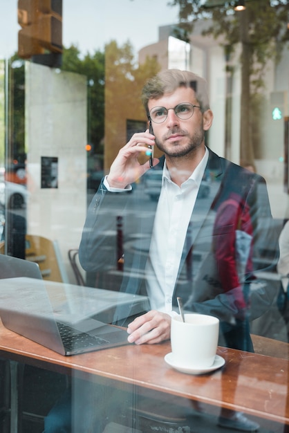 Elegante giovane imprenditore parlando sul cellulare nella caffetteria