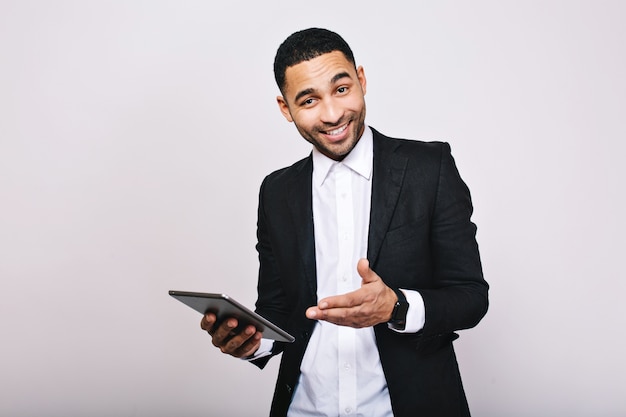 Elegante giovane uomo bello in camicia bianca, giacca nera, con tablet sorridente. Raggiungere successo, ottimo lavoro, esprimere vere emozioni positive, uomo d'affari, lavoratore intelligente.