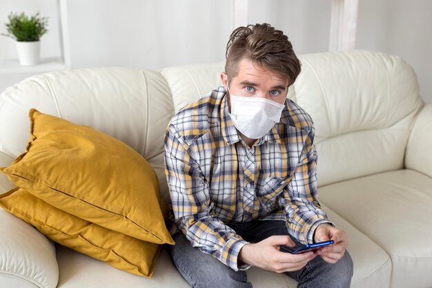 Elegante maschio con maschera facciale in posa sul divano