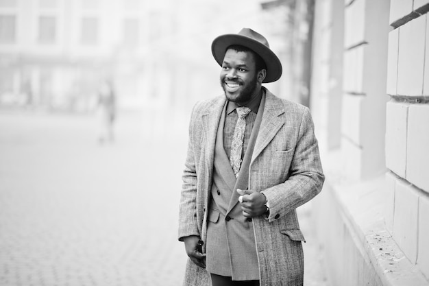 Elegante modello uomo afroamericano in giacca grigia con cravatta e cappello rosso Foto in bianco e nero