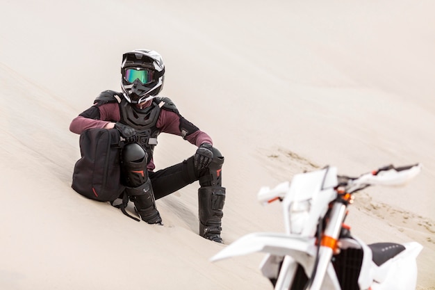 Elegante motociclista rilassante nel deserto