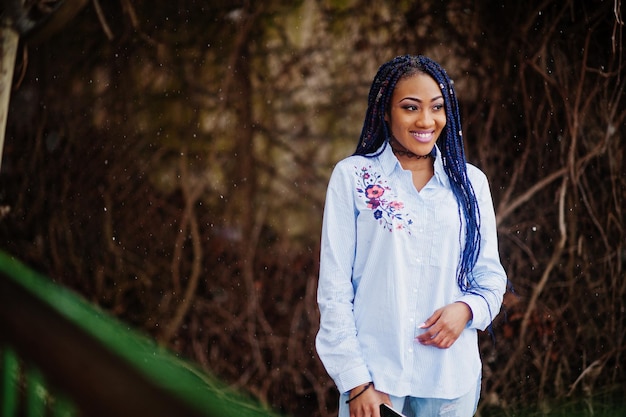 Elegante ragazza afroamericana con dreadlocks che tiene il telefono cellulare a portata di mano all'aperto tempo nevoso