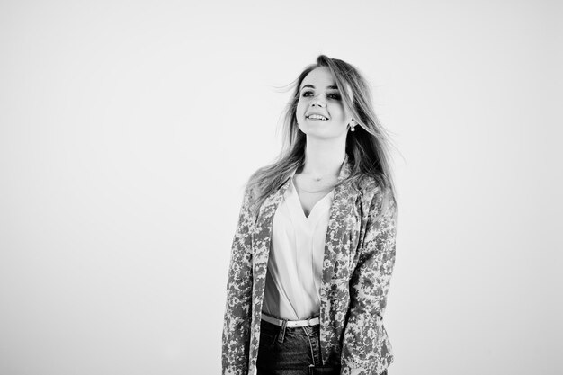 Elegante ragazza bionda in giacca e jeans con diario del taccuino a portata di mano su sfondo bianco in studio