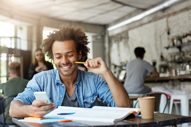 Elegante studente maschio che lavora presso la caffetteria