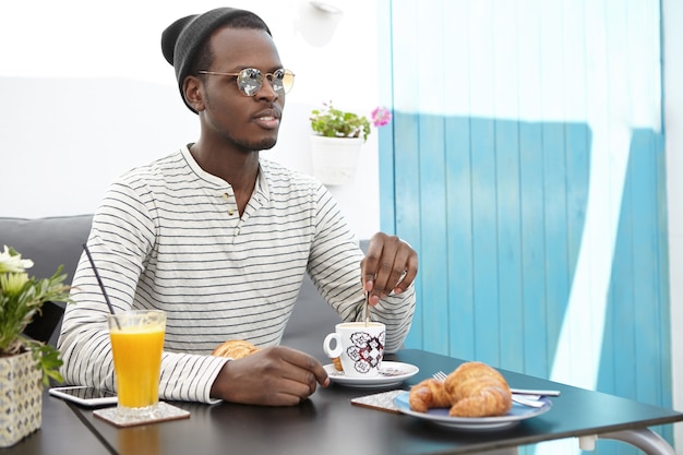 Elegante uomo afro-americano che si siede nella caffetteria