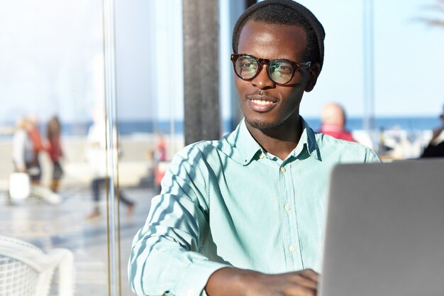 Elegante uomo afro-americano con il computer portatile