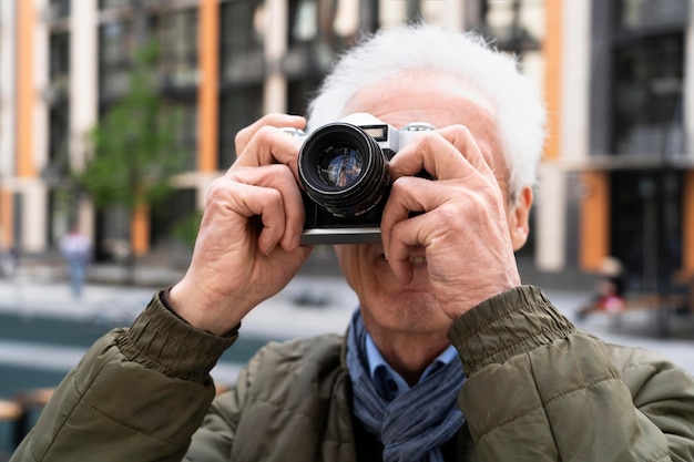 Elegante uomo anziano in città che usa la fotocamera per scattare foto