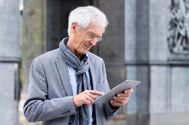 Elegante uomo anziano in città che utilizza tablet