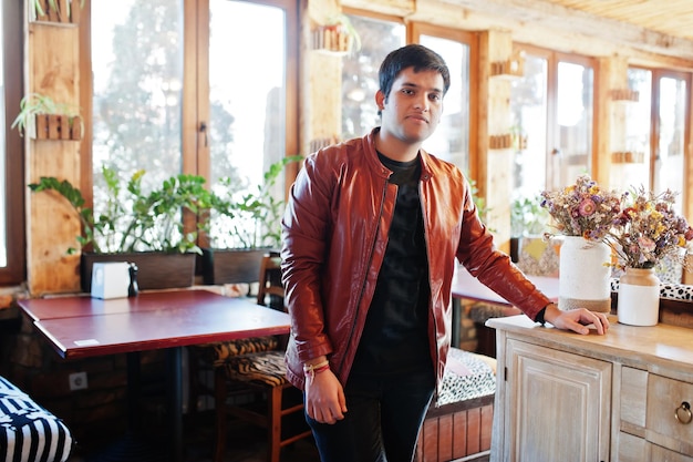 Elegante uomo indiano in abbigliamento casual in posa di un caffè al coperto