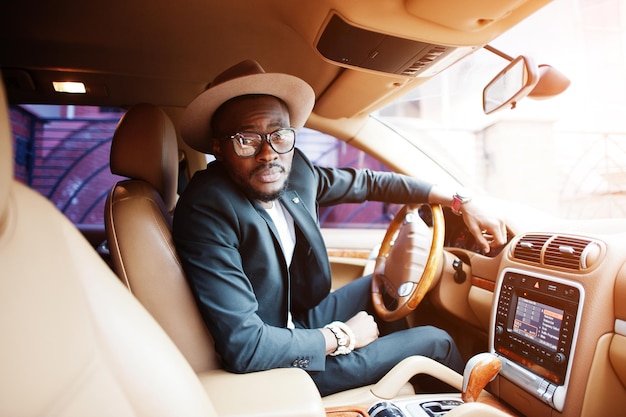 Elegante uomo nero seduto al volante di un'auto di lusso Ricco uomo d'affari afroamericano