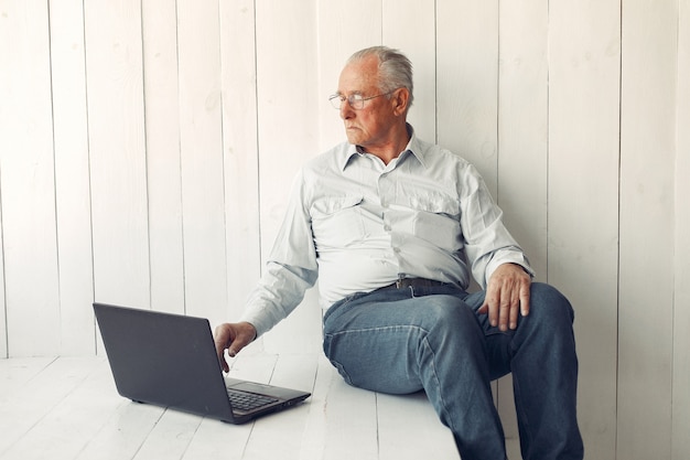 Elegante vecchio seduto a casa e utilizzando un computer portatile