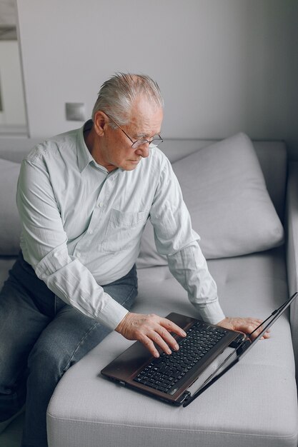 Elegante vecchio seduto a casa e utilizzando un computer portatile