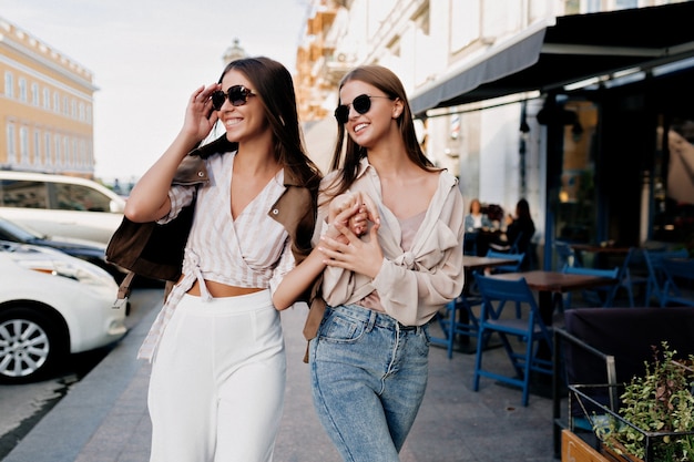 Eleganti donne alla moda in abiti alla moda che vagano per la città dopo lo shopping.