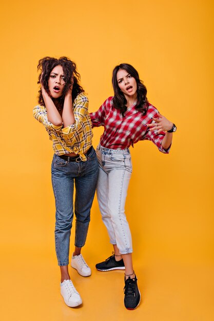 Eleganti ragazze urbane emotivamente pongono. Adolescenti in jeans e scarpe da ginnastica dall'aspetto patetico.