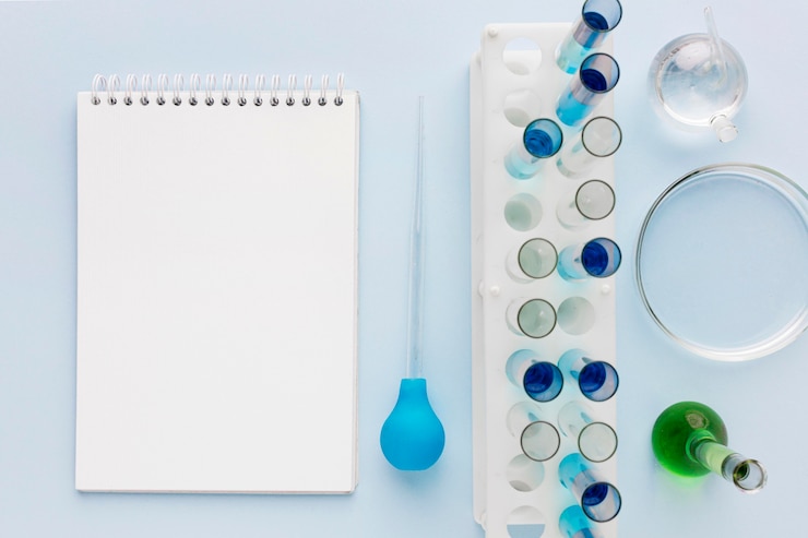 Foto gratuito elementi di scienza in laboratorio con blocco note vuoto