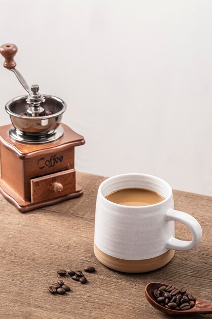 Elevato angolo di macinino da caffè con tazza e chicchi di caffè