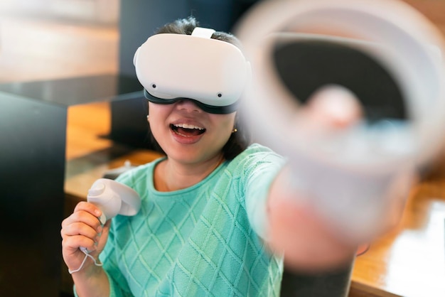 Emozionante giocatore asiatico femminile che gioca in realtà virtuale aumentata metaverse futuristico gioco 3D Bella giovane donna che gioca in occhiali per realtà virtuale con divertimento e gioiosa