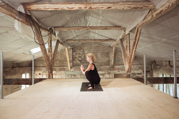 Energia. Una giovane donna atletica esercita lo yoga su un edificio abbandonato. Equilibrio della salute mentale e fisica. Concetto di stile di vita sano, sport, attività, perdita di peso, concentrazione.