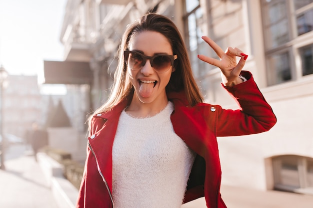 Entusiasta ragazza europea con i capelli scuri in posa con il segno di pace