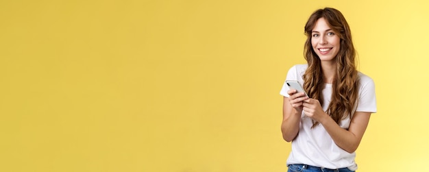 Entusiasta ragazza urbana di bell'aspetto indossare maglietta bianca in piedi casual sorridente felice fotocamera texti