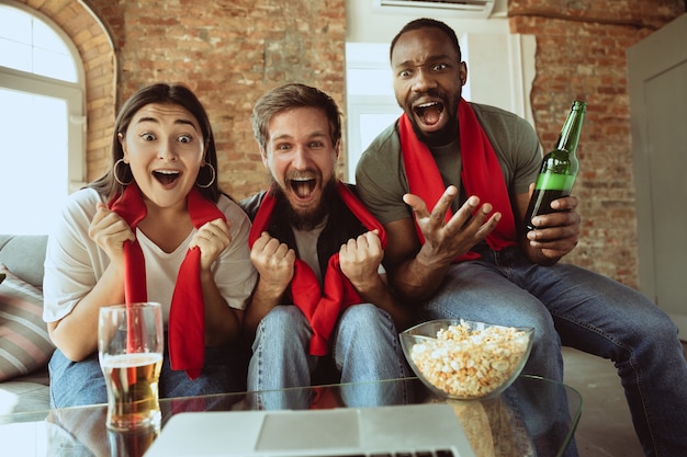 Entusiasti tifosi di calcio che guardano la partita sportiva a casa, supporto remoto della squadra preferita durante l'epidemia di pandemia da coronavirus