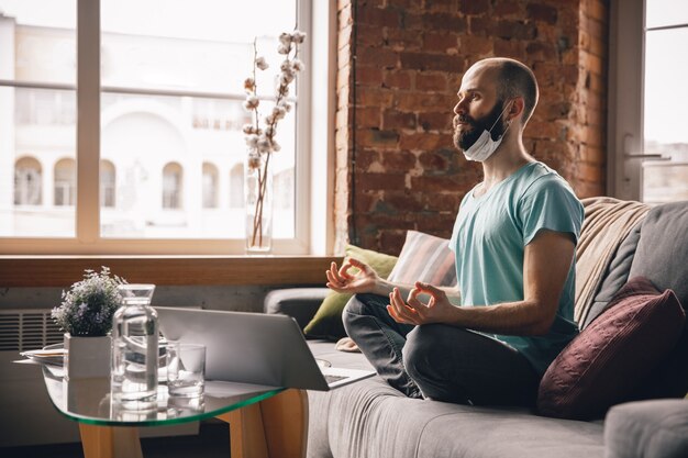 Equilibrato. Giovane che fa yoga a casa mentre è in quarantena e lavora online come freelance