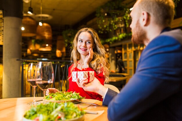 Equipaggi dare il piccolo contenitore di regalo alla donna bionda alla tavola