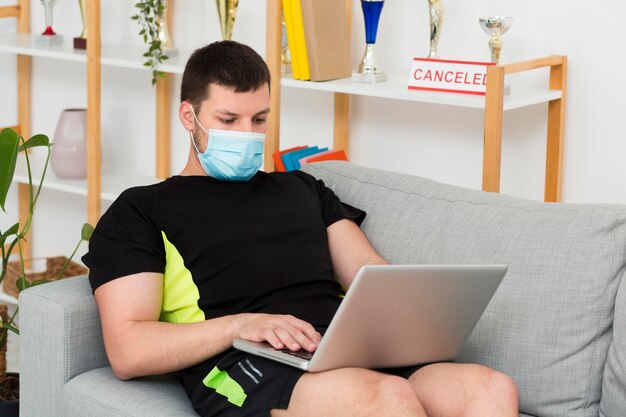 Equipaggi indossare una maschera medica mentre controllano il suo computer portatile