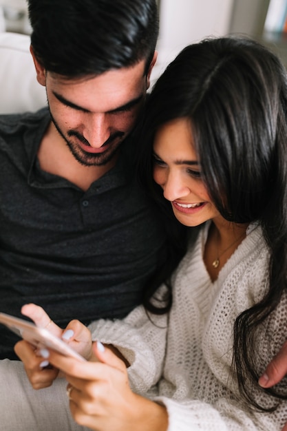 Equipaggi l&#39;esame del cellulare sorridente della tenuta della donna