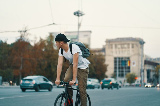 Equipaggi la bicicletta di guida in città urbana che si tiene per mano sul manubrio