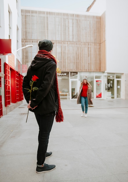 Equipaggi la donna aspettante per dare la rosa rossa