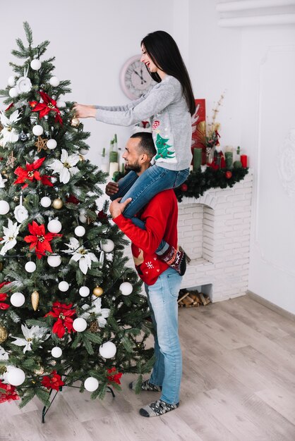 Equipaggi la donna della holding sul collo vicino all&#39;albero di abete